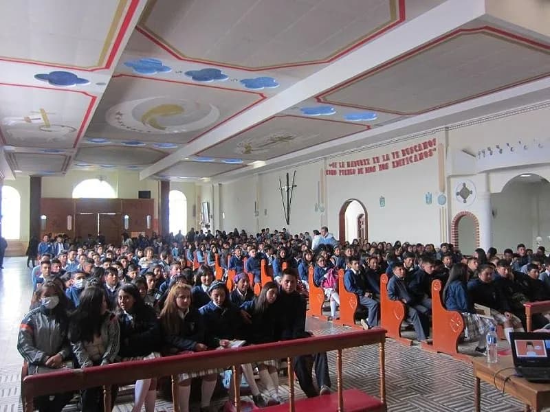 Cientos de estudiantes de uniforme llenando el recinto durante una conferencia