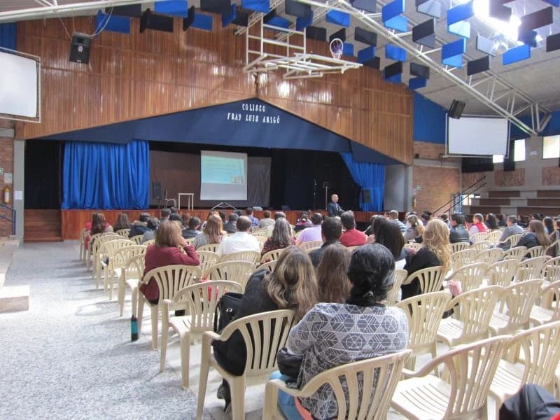 Auditorio con techo alto lleno de asistentes en sillas blancas