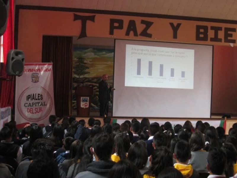 Conferencia con gráficas proyectadas ante un auditorio completo